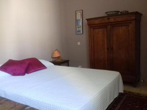 a bedroom with a white bed and a wooden cabinet at Les Trois Rois in Nîmes