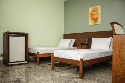 two beds in a room with a mirror at Riviera Palace Hotel in Sete Lagoas