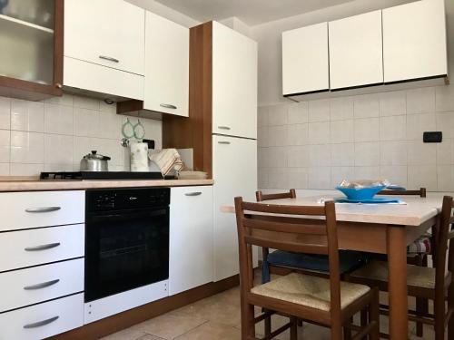 a kitchen with white cabinets and a table with chairs at THE DORMOUSE - Il Ghiro in Reusa