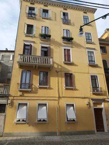 a yellow building with windows and a balcony at A Casa di Claudia in Venice