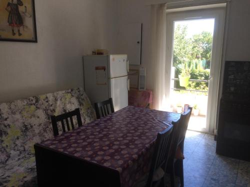 eine Küche mit einem Tisch, einem Kühlschrank und einem Fenster in der Unterkunft Appartement sur Sommières jusqu'à 6 personnes in Sommières