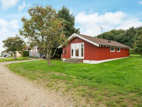 een rood huis met een boom in het gras bij 6 person holiday home in Bjert in Binderup Strand