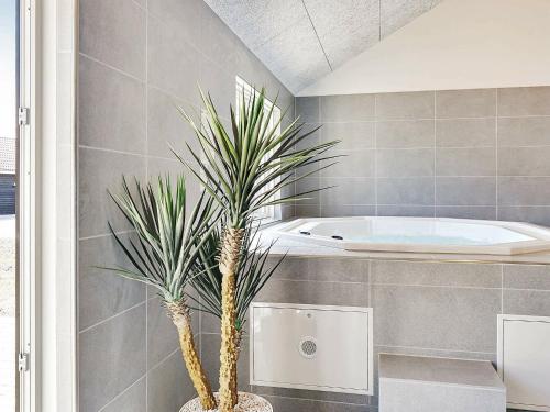 a bathroom with a tub and two palm trees at Holiday home Grenaa XI in Grenå