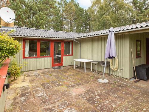 a patio with a table and an umbrella in front of a house at 6 person holiday home in R dby in Rødby