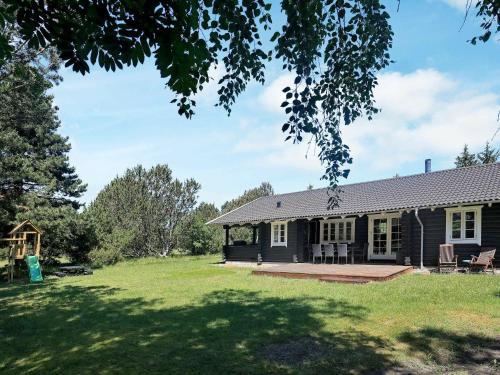 a black house with a porch and a yard at 6 person holiday home in R dby in Rødby