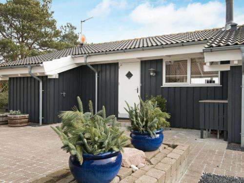 uma casa com dois potes azuis de plantas em frente em 6 person holiday home in Ebeltoft em Ebeltoft