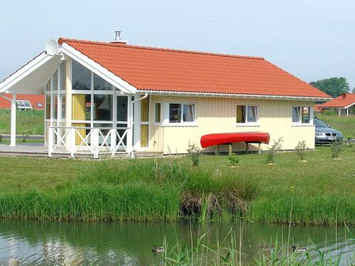 a house with a red roof next to a body of water at 5 person holiday home in Otterndorf in Otterndorf