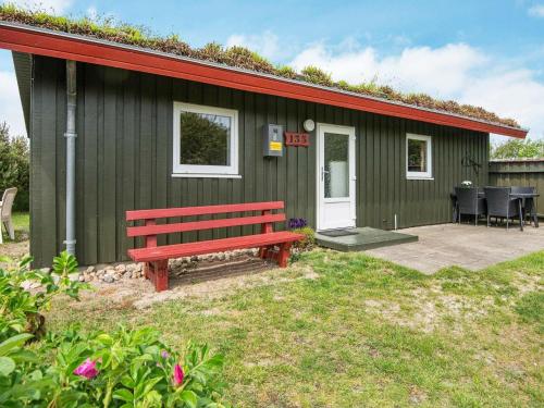 une maison verte avec un banc rouge devant elle dans l'établissement 6 person holiday home in R m, à Bolilmark