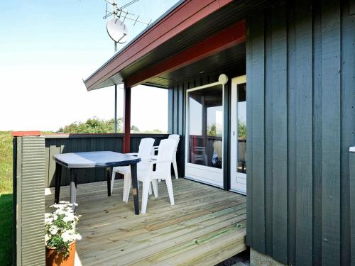 une terrasse en bois avec une table et des chaises blanches dans l'établissement 6 person holiday home in R m, à Bolilmark