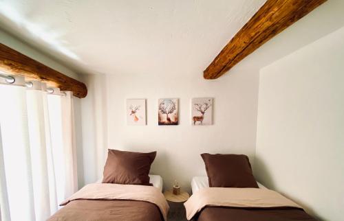 2 łóżka w pokoju z białymi ścianami i drewnianymi belkami stropowymi w obiekcie Résidence Saint-Jean w mieście Saint-Dalmas-le-Selvage