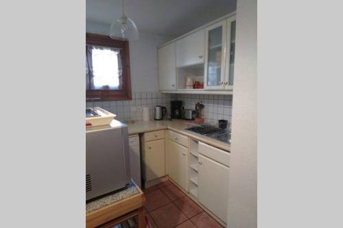 Elle comprend une petite cuisine avec des placards blancs et une fenêtre. dans l'établissement Vallée de Chamonix au pied des pistes, aux Houches