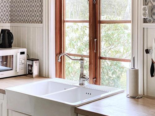 eine Küche mit einem großen weißen Waschbecken vor einem Fenster in der Unterkunft Holiday home SKILLINGARYD in Skillingaryd