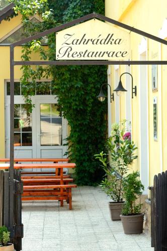 a wooden bench under a sign in front of a building at Hotel Leopold Račín in Račín