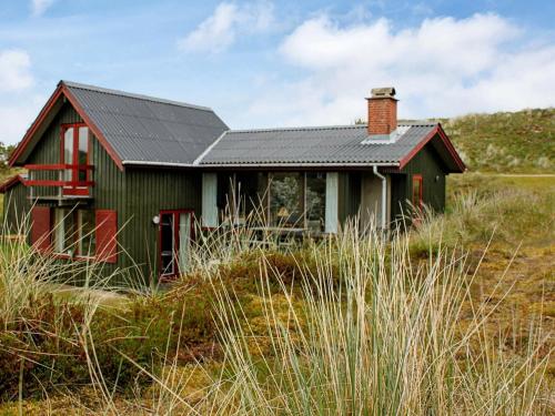 a green house with a black roof in a field at 4 person holiday home in Fan in Fanø