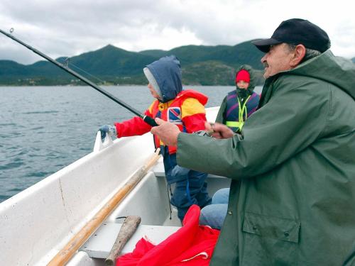 un hombre sosteniendo una caña de pescar en un barco en 5 person holiday home in ENGAV GEN en Åmnes