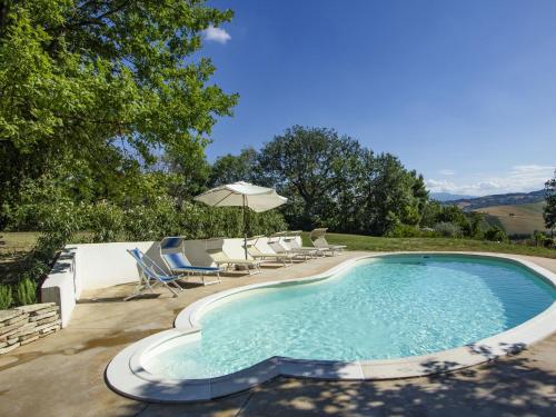 a swimming pool with chairs and an umbrella at Belvilla by OYO Casale le Querce in Cossignano