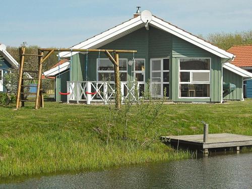 ein grünes Haus mit einem Dock neben einem Wasserkörper in der Unterkunft 6 person holiday home in Otterndorf in Otterndorf