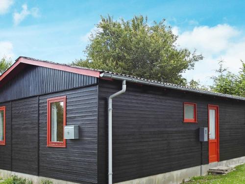 czarny dom z czerwonymi oknami i czerwonym dachem w obiekcie 6 person holiday home in Nordborg w mieście Nordborg