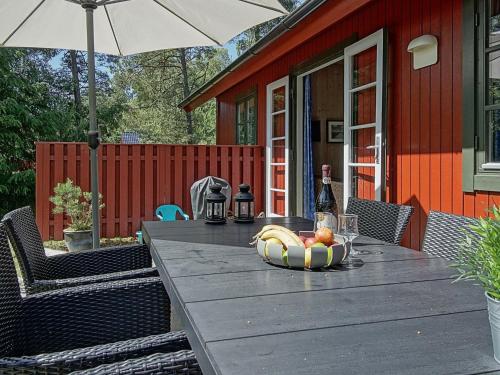 een houten tafel met een fruitschaal en een paraplu bij 6 person holiday home in Nex in Snogebæk