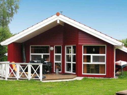 a red cottage with a deck and large windows at 6 person holiday home in Otterndorf in Otterndorf