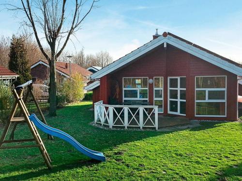 a small red house with a slide and a playground at 6 person holiday home in Otterndorf in Otterndorf