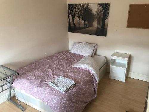 a bedroom with a bed with a purple comforter and a mirror at 295 Sturry Rd in Kent