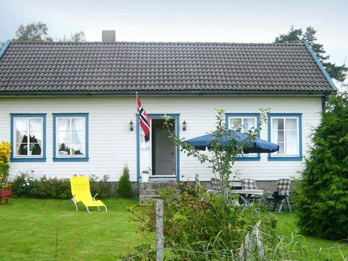 a white house with a flag and a table and chairs at 6 person holiday home in lyngdal in Lyngdal