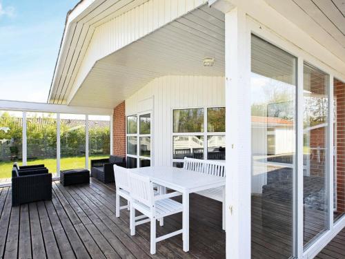 Fjand Gårdeにある6 person holiday home in Ulfborgの白いテーブルと椅子付きのポーチ