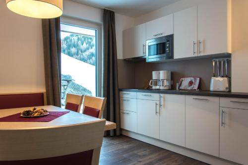 cocina con armarios blancos, mesa y ventana en Appartements Plaija, en Sankt Anton am Arlberg