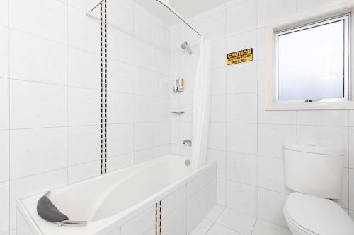 a white bathroom with a tub and a toilet at Beach Street Motel Apartments in New Plymouth