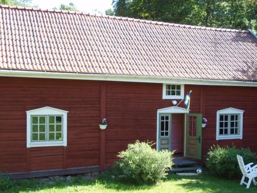 a red house with a red roof and a flag at 8 person holiday home in VIMMERBY in Rumskulla