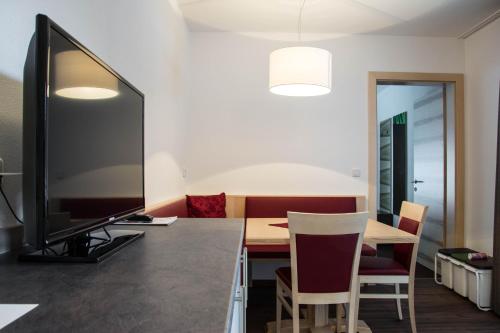 a room with a desk with a television and a table with chairs at Appartements Plaija in Sankt Anton am Arlberg