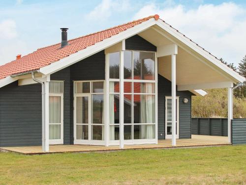 Fjand Gårdeにある8 person holiday home in Ulfborgのデッキ上の大きな窓のある家