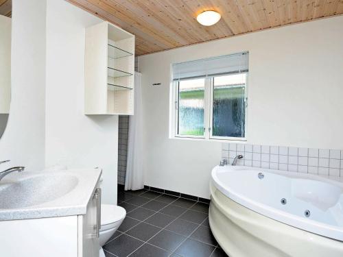 a white bathroom with a tub and a toilet at 8 person holiday home in Ulfborg in Fjand Gårde