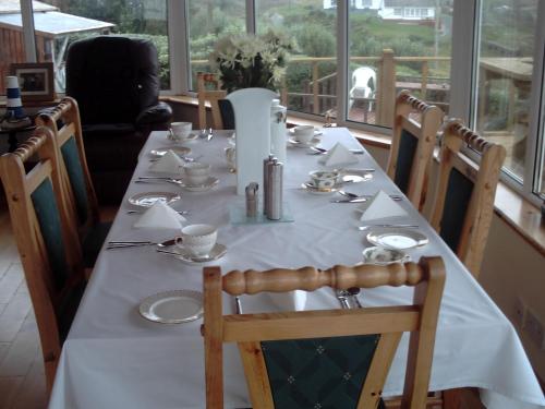 una mesa larga con un mantel blanco y un jarrón en Teach Donncadh B&B, en Kincasslagh