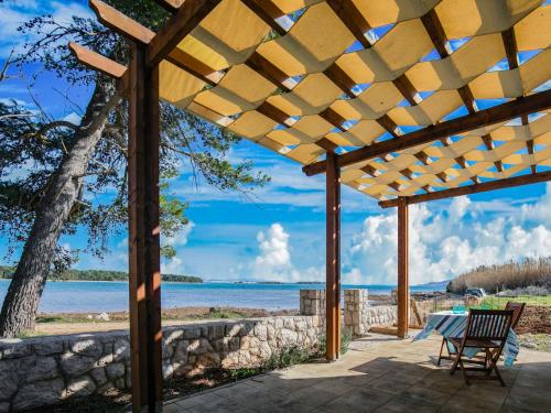 a wooden pergola with a table and chairs on the beach at Secluded Holiday Home in Pa man with Sea nearby in Pašman