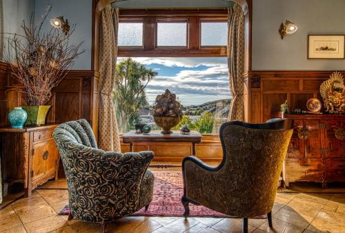 a living room with a large window and two chairs at Pen-y-bryn Lodge in Oamaru