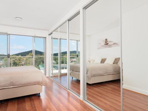 two beds in a bedroom with glass walls at 501 The Shoal in Shoal Bay