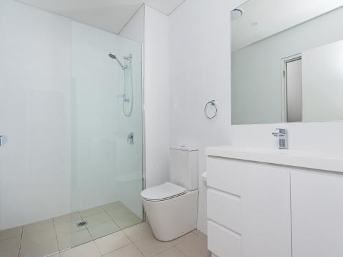 a white bathroom with a toilet and a sink at 501 The Shoal in Shoal Bay