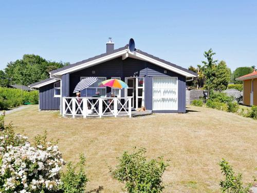una pequeña casa azul con una persona con sombrilla en 6 person holiday home in GROEMITZ, en Grömitz