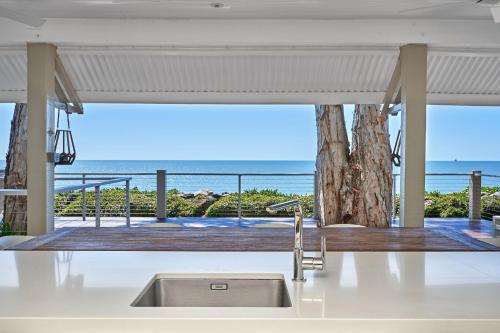 Una cocina con fregadero y vista al mar. en Decked Out By The Sea, en Clifton Beach