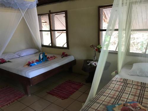 a bedroom with two beds and two windows at Tranquility Island Eco Dive Resort in Moso Island
