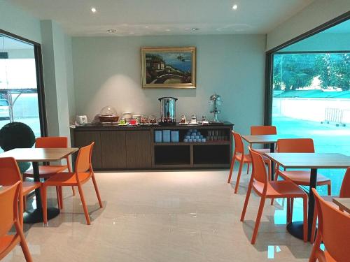 a restaurant with tables and chairs and a counter at Orchid Residence Suratthani in Surat Thani