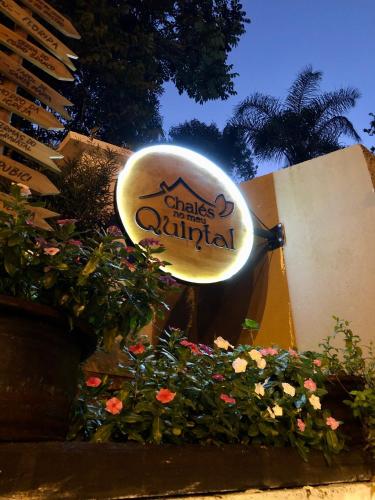 a sign for a hotel with flowers in front of it at Chalés no meu quintal in Louro Müller