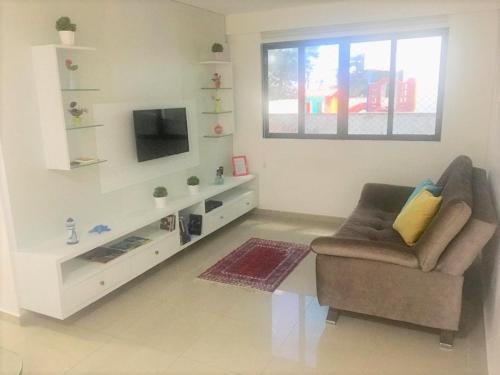 uma sala de estar com uma cadeira e uma televisão em Lindo Ap 101 Quadra do Mar c Garagem no Recife