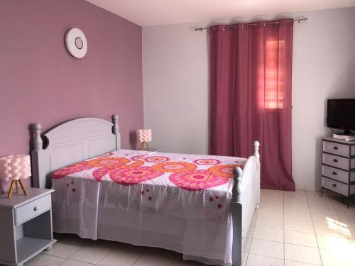 um quarto com uma cama com um cobertor rosa e uma janela em Mawima em Vieux-Habitants