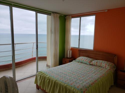 a bedroom with a bed with a view of the ocean at Arco Iris Atacames in Atacames