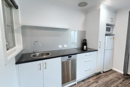 a white kitchen with a sink and a refrigerator at Pelicans Albany Middleton Beach in Albany