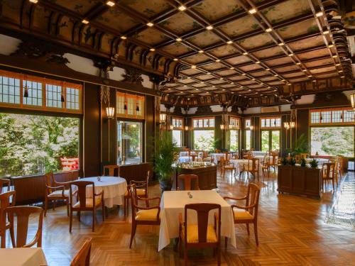 uma sala de jantar com mesas, cadeiras e janelas em Fujiya Hotel em Hakone