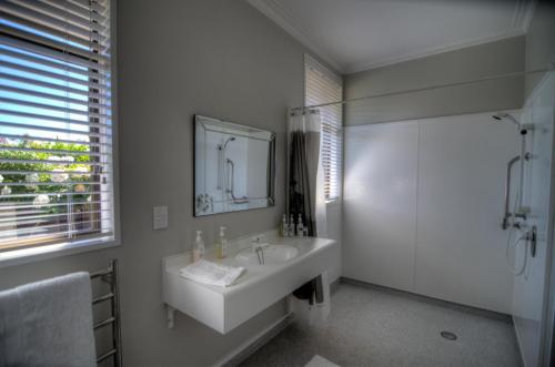 a white bathroom with a sink and a mirror at Kerry Lodge Bed & Breakfast in Napier